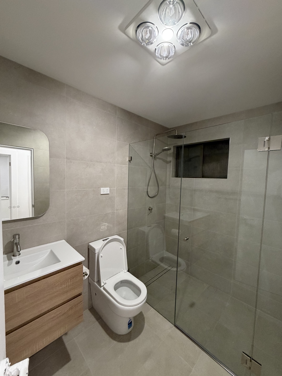 Renovated Ashcroft bathroom with a timber vanity, large format tiles and a glass shower screen